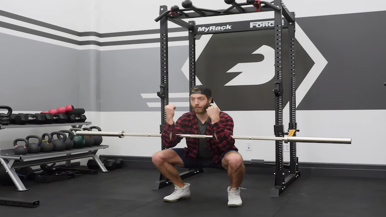 Man performing deep squat holding barbell in arms